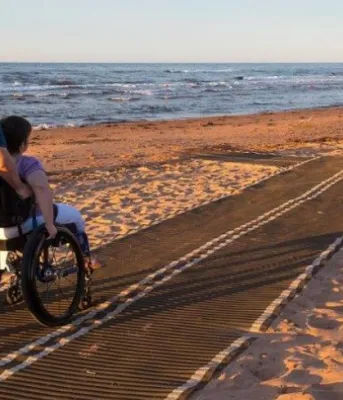 Individuals using accessibility mat on local beach