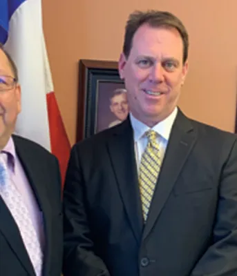 Three people stanindg shoulder to shoulder while in an office
