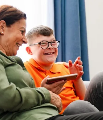 image of an older person and a younger person sitting on a couch and laughing
