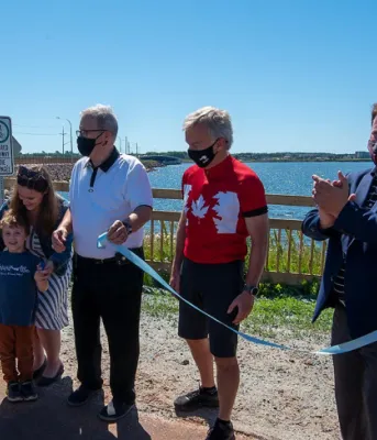 A number of people line up in front of the Hillsborough Bridge for the ribbon cutting to open the active transportation lane