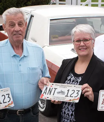Five people holding an antiqye license plate.