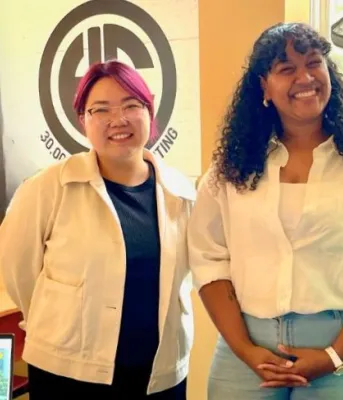 image de trois personnes debout épaule contre épaule derrière une table avec une bannière d'affichage derrière elles