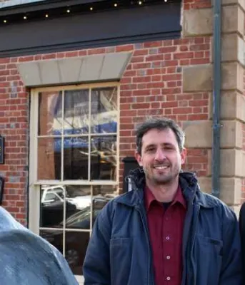 Two people sanding beside a Great Blue Heron statue