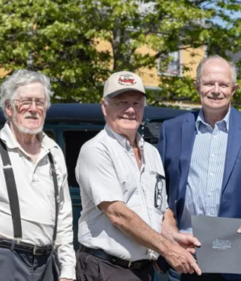 image of three people in front of an antique car
