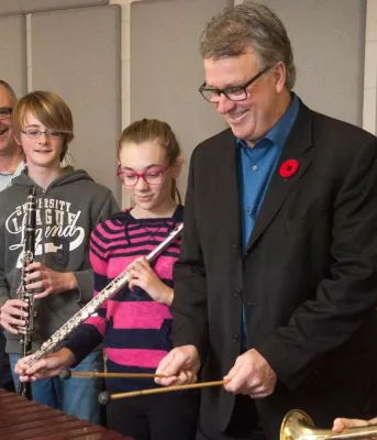 Minister Doung Curie and Music Teacher Frank Nabburs and four students hold musical instruments