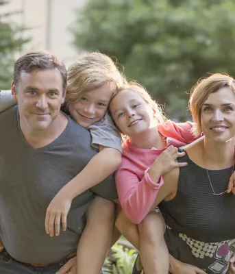 Bonnie Stewart and her partner Dave Cormier post while giving their children piggy-back rides