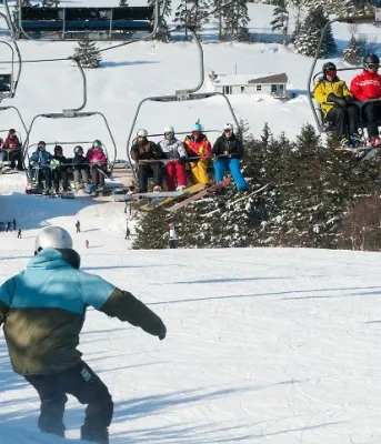 Winter scene at Brookvale Ski Park, featuring a skier on the hill and the chair lift transporting more skiers
