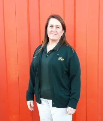 Candace Cormier stands outside against the backdrop of an orange building. 