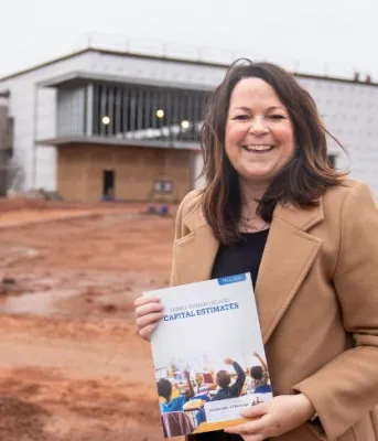 image d'une personne tenant un document alors qu'elle se tient devant un immeuble en construction