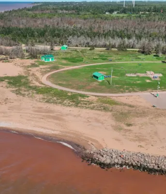 aerial photo of a beach area with rocks in front and a lighthouse in the background