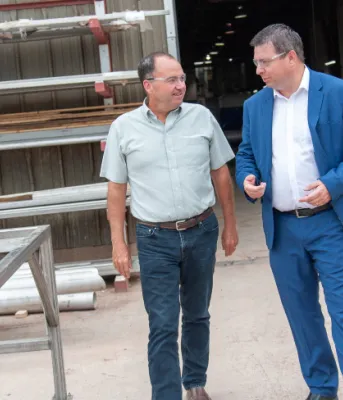 Two men standing inside a fabrication yard work area