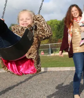 Alyse Rossiter pushes her daugher Akyvia on the swing outside her daycare