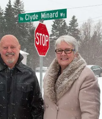 Minister Biggar and thre other people stand in front of the Clyde Minard Way street sign.