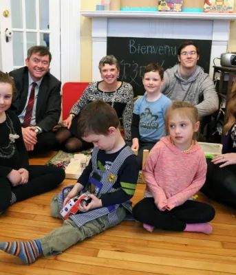 Minister Mundy sits with people in front of a non-working fireplace