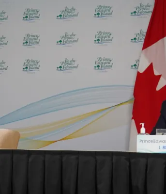 image of two people wearing masks while sitting at a news conference table