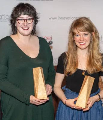 image of  four people standing shoulder to shoulder and some holding onto awards