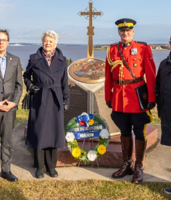 six people stand at the Acadian memorial at Skmaqn–Port-la-Joye–Fort Amherst National Historic Site 