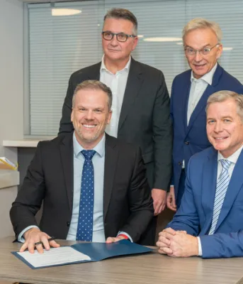 image of five people at a table signing a document