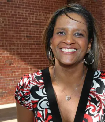 Deborah Langston stands outdoors in front of a red brick building