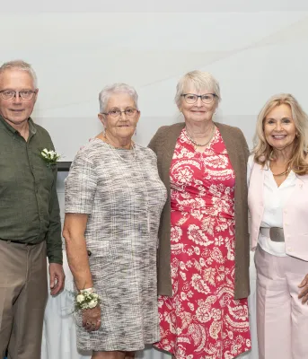image of six people standing shoulder to shoulder in front of a projector screen