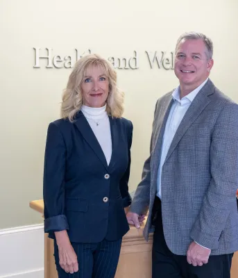image of two people standing side by side in front of a desk in an office foyer
