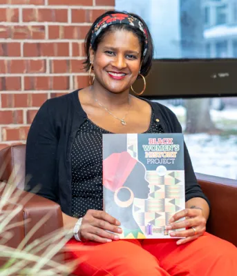 image of a woman sitting on a chair holding a booklet on her lap