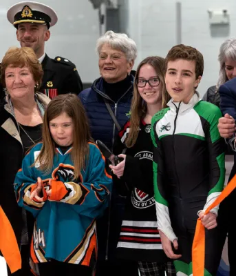 image of a group of people standing in a rink holding a ribbon during an opening ceremony