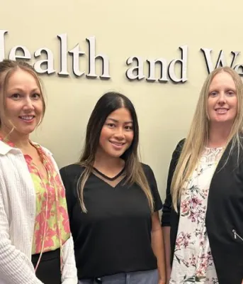 image of  five people standing shoulder to shoulder behind a desk in an office