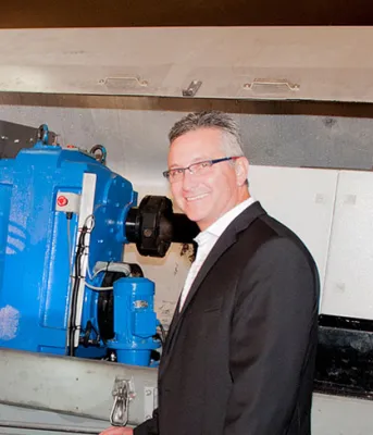 Minister MacDonald and Carl Brothers stand in front of wind trubine machinery under production.