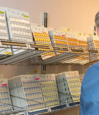 Photo shows Grant Wyand standing next to rows of medications