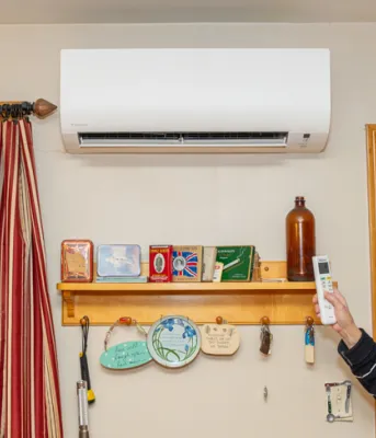 image of a person inside a house using a remote control to use a heat pump