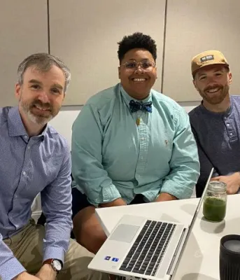 image of three people sitting behind a table with some broadcasting equipment on the table