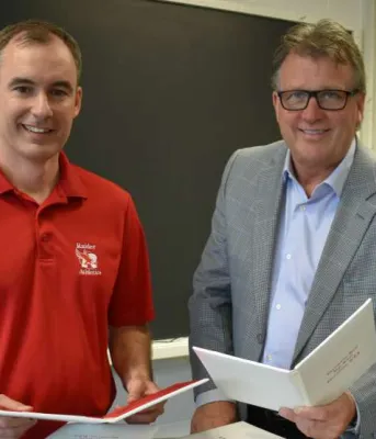 Two people holding signed high school diplomas