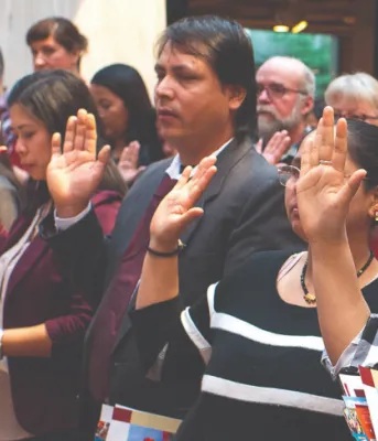 image of a group of people standing shoulder to shoulder with one arm - palm out - held at shoulder height