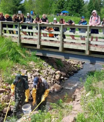 Image of group of people on small bridge looking over at watershed