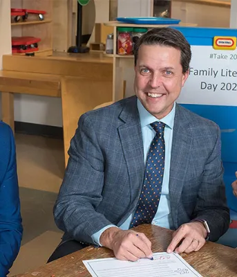 People sitting at a table holding young children in their arms.