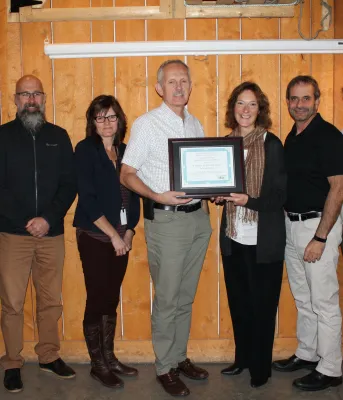 Photo shows Alex Forbes in the centre holding the award certificate flanked by six subcommittee members.