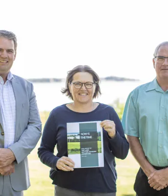 image of three people standing shoulder to shoulder and middle person holding the booklet report