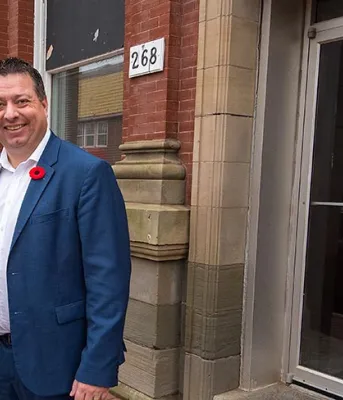 Two people standing in front of a storefront building
