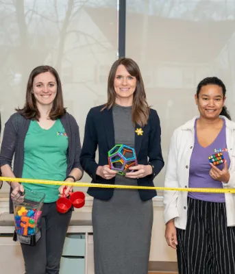 image of  five people standing shoulder to shoulder inside a building while holding some play objects