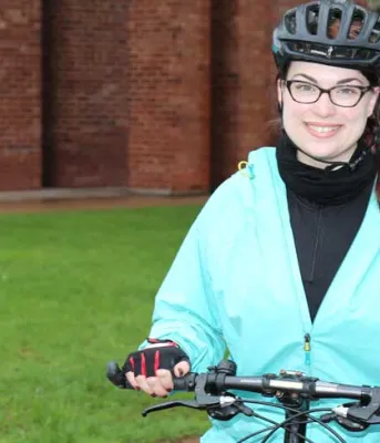 Female biker standing in front of workplace with her bike.