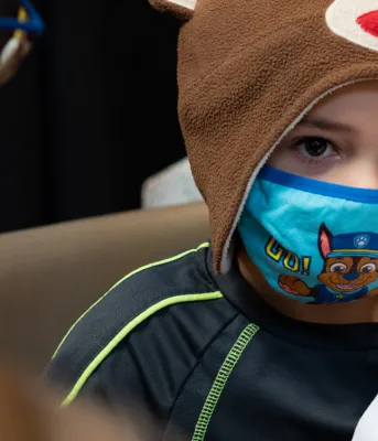 image of a child with a mask on receiving his vaccination