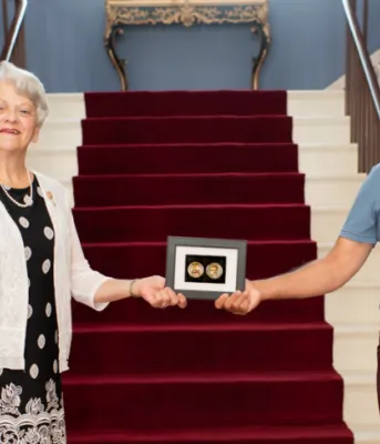Honourable Antoinette Perry and Dr. Trevor Jain stand holding a COVID Warrior Coin