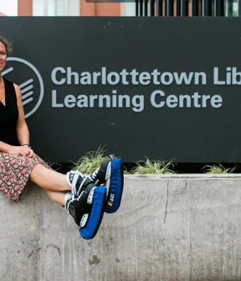 image of a person wearing ice skates and sitting bedside a sign outside a library
