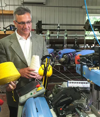 Four people looking at loom machine