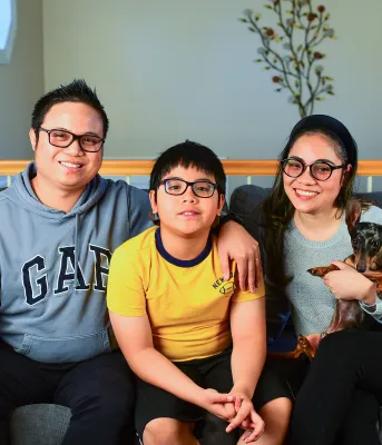 Woman and man posing with their son and dog on a couch