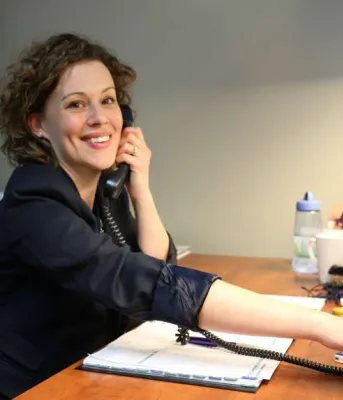 Mary Laura Coady speaks on her telephone while sitting at her desk