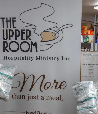 image  of 2 people with masks on standing in front of a sign