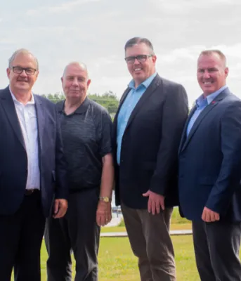 Six men stand on the bank of the Morell river following a federal provincial funding announcement