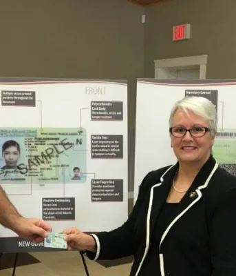 Photo shows three people in front of an enlarged version of the new licence, two holding the new licence and one standing to the right.